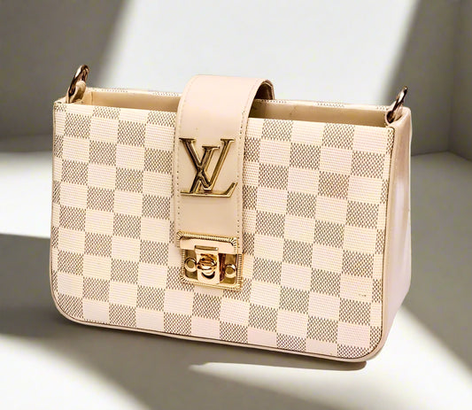 Designer handbag with checkered pattern and visible brand logo on a reflective surface.