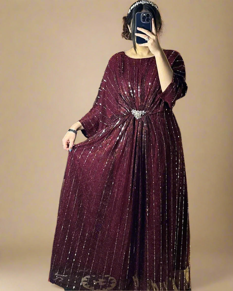 Person wearing a burgundy dress with a belt, standing in a room with decorative elements.