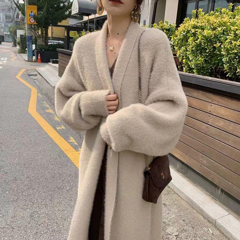 Person wearing a long beige coat on a city street.