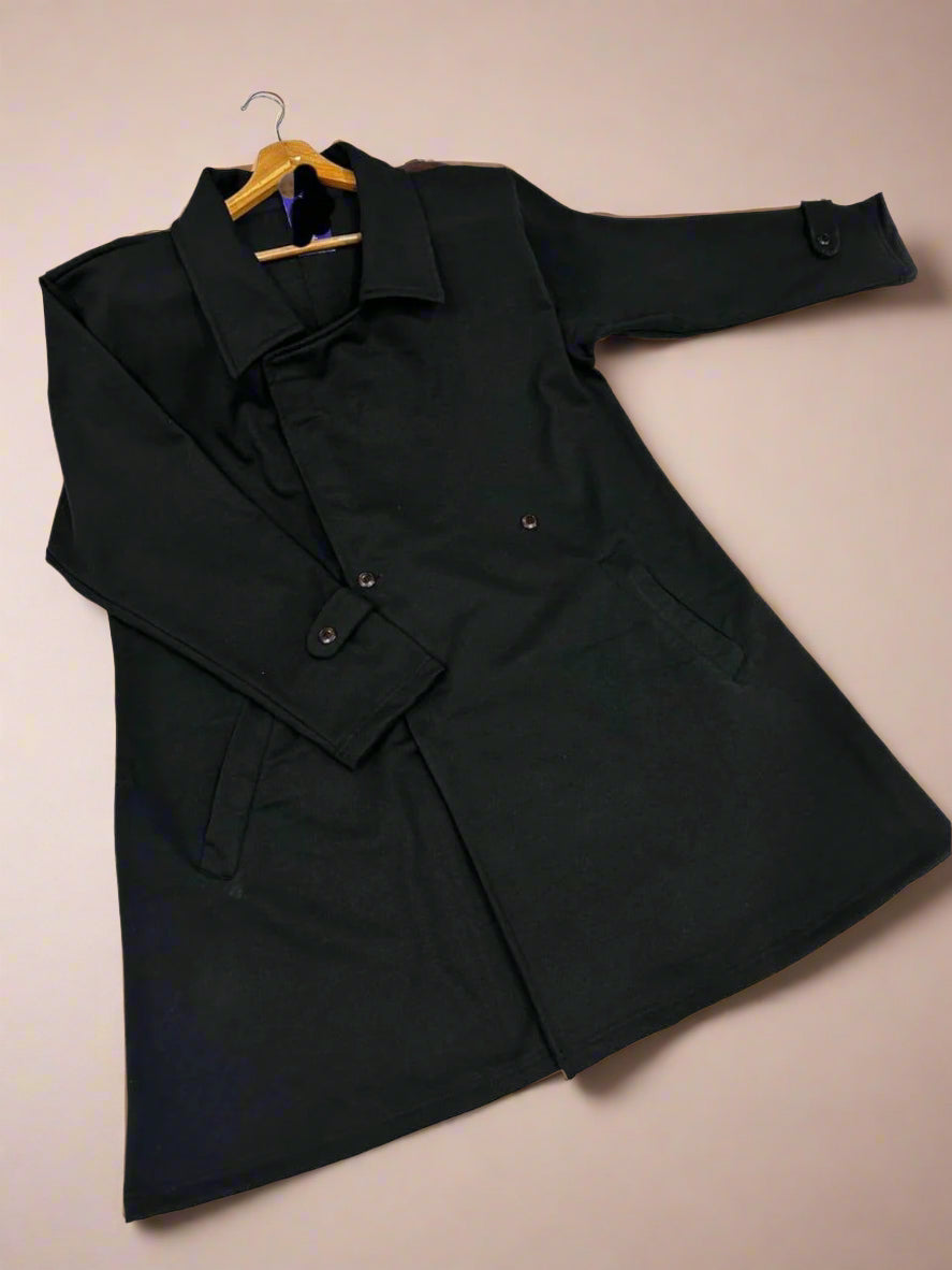 Black coat on a hanger against a beige background.