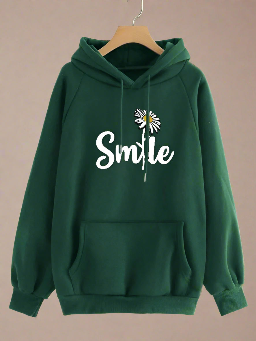 Green hoodie with 'Smile' and flower design on a hanger against a beige background