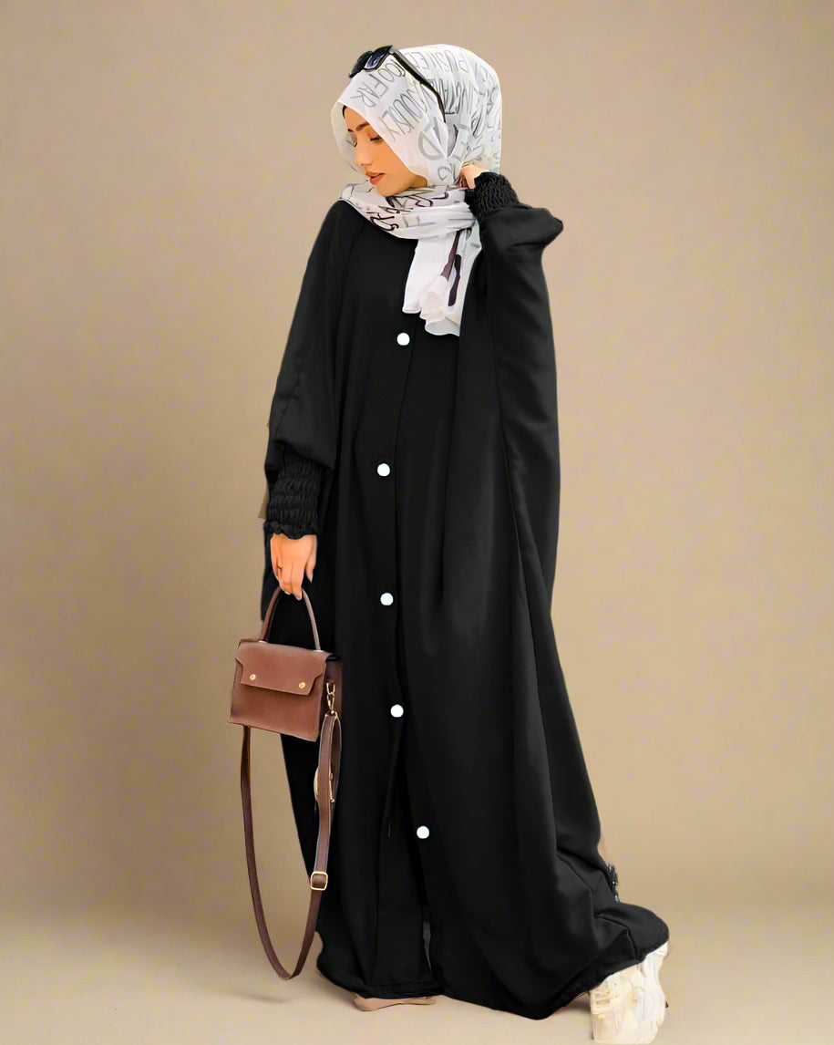 Woman in a black dress with white buttons standing