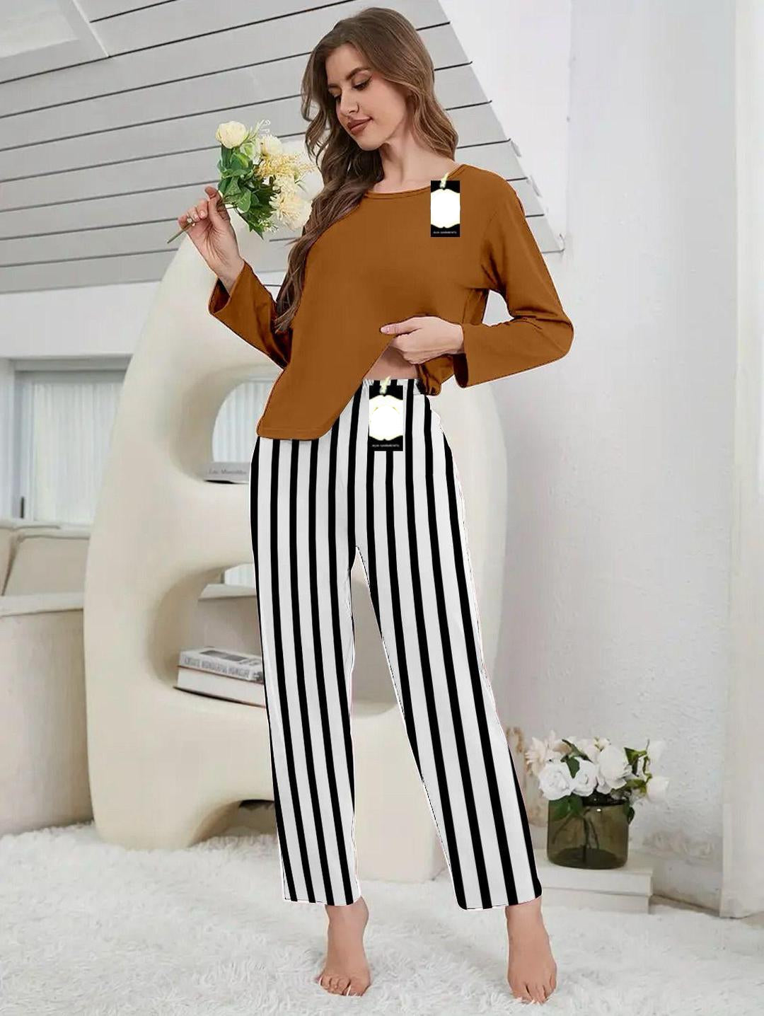 Woman wearing a brown top and black and white striped pants in a home setting.