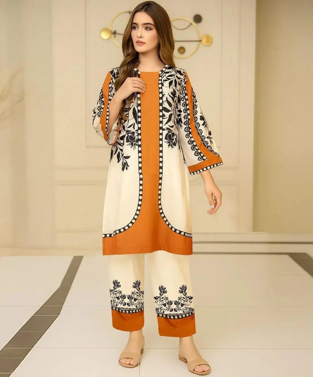 Woman wearing a traditional outfit with orange, white, and black patterns in an indoor setting.
