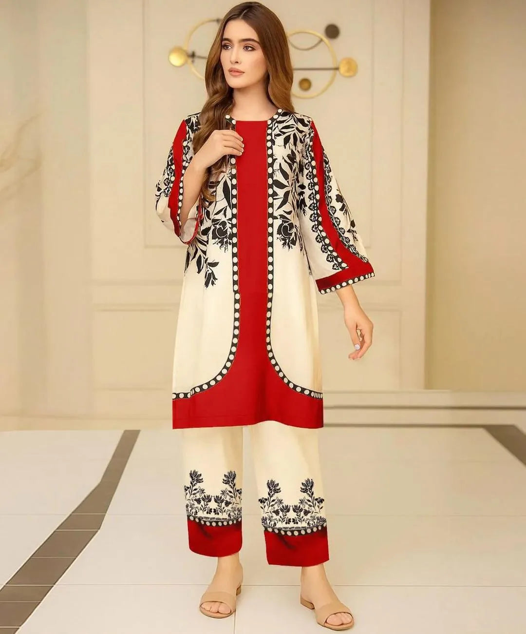 Woman wearing a red and white traditional outfit with black patterns in a minimal indoor setting.