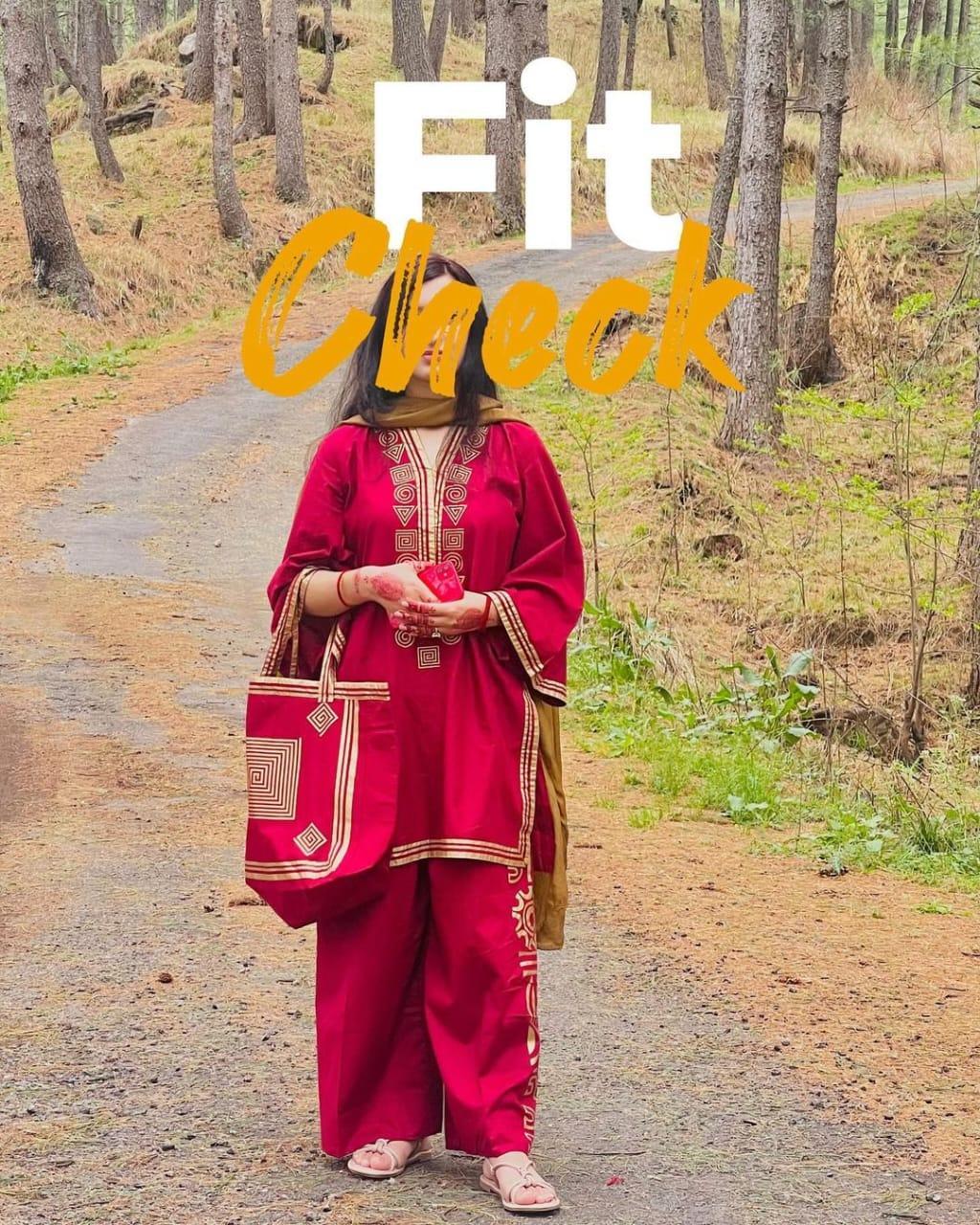 Person in a red traditional outfit with gold accents standing on a forest path, with text 'Fit Check' overlayed.