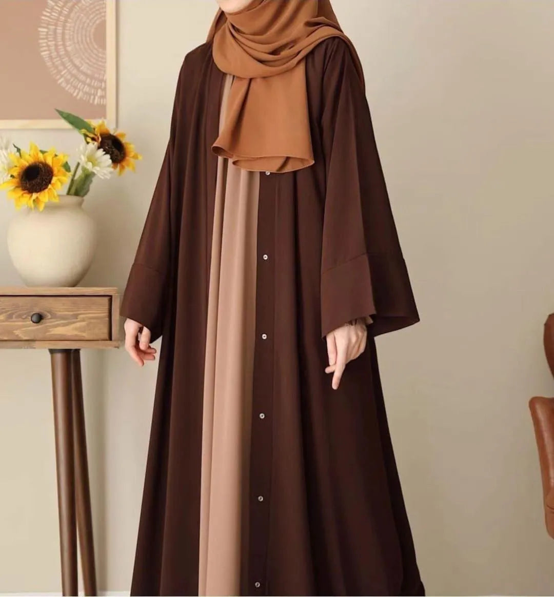 Person wearing a brown dress with a matching hijab in a room setting.