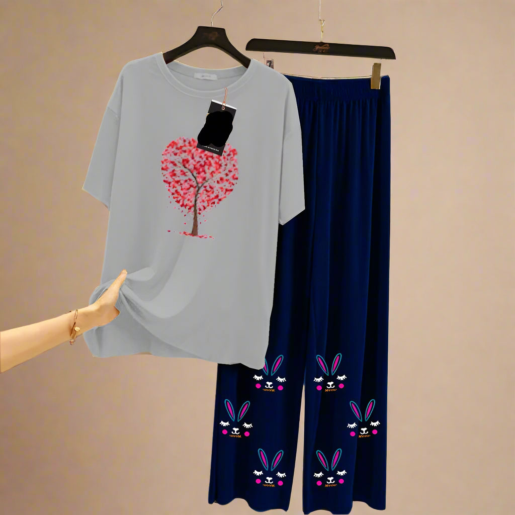 Gray t-shirt with pink tree design and navy pants with bunny faces on a hanger against a light background.