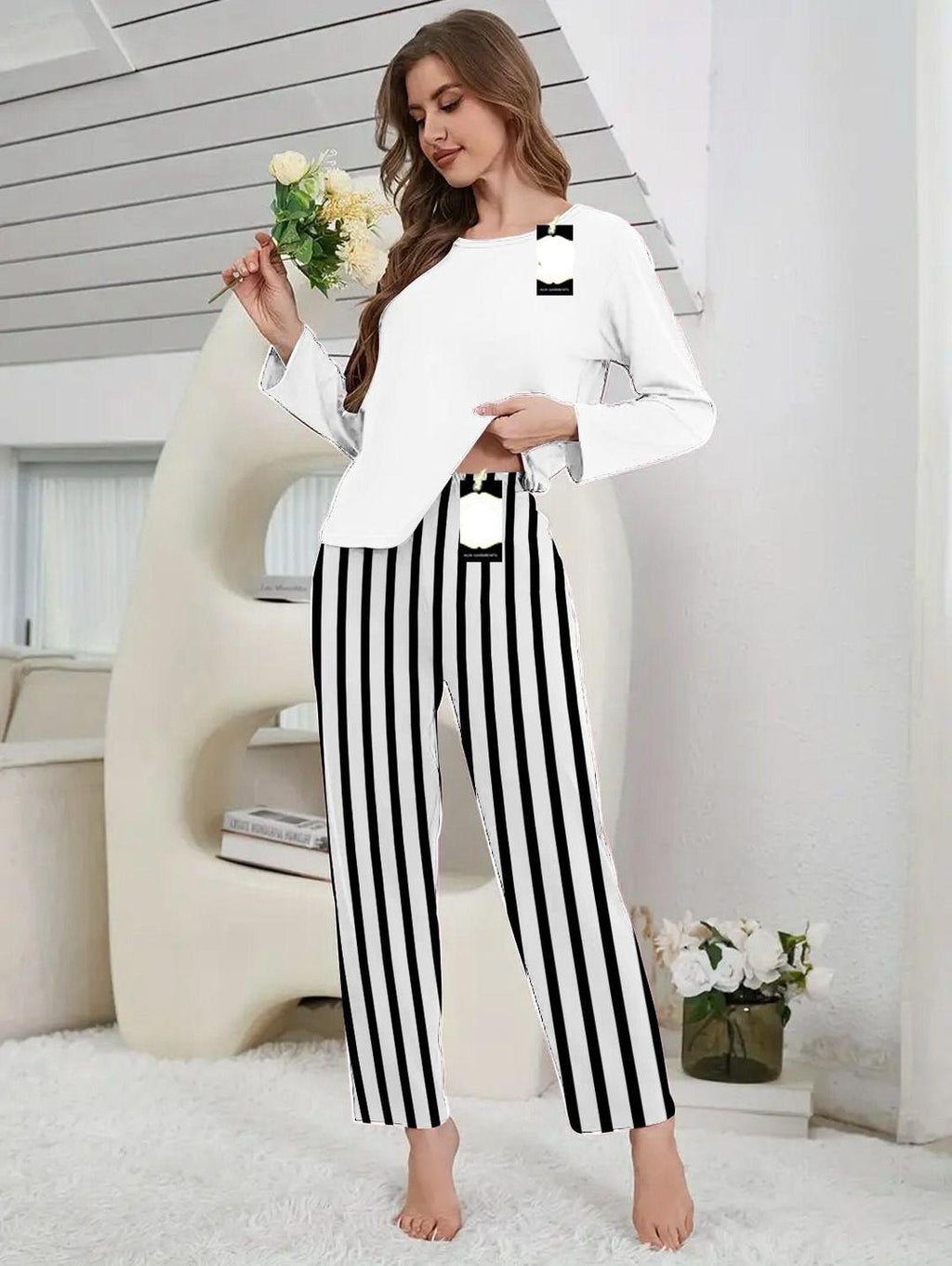 Woman wearing a white top and black and white striped pants in a modern interior setting.
