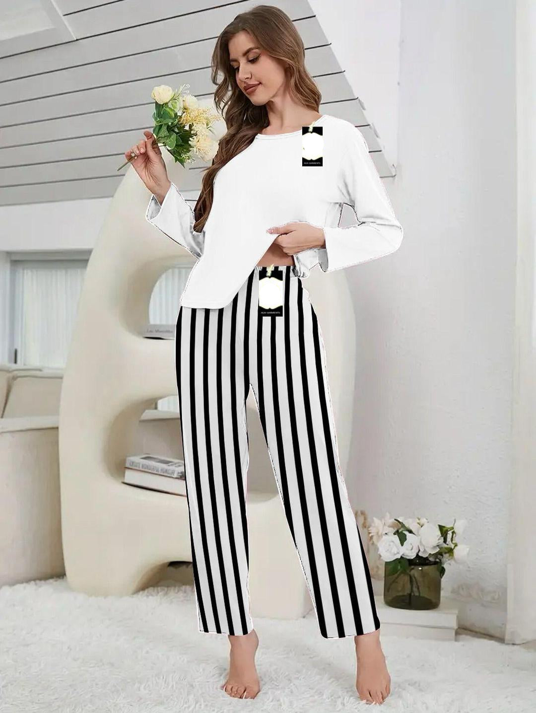 Woman wearing a white top and black and white striped pants in a modern interior setting.